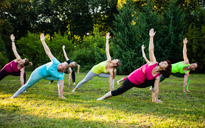 Women practicing a yoga pose outside on the grass