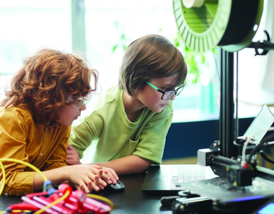 Two boys using a 3D printer