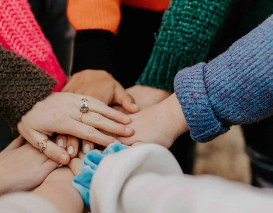 A group of hands clapsed together as if people were standing in a circle with their hands joined in the middle