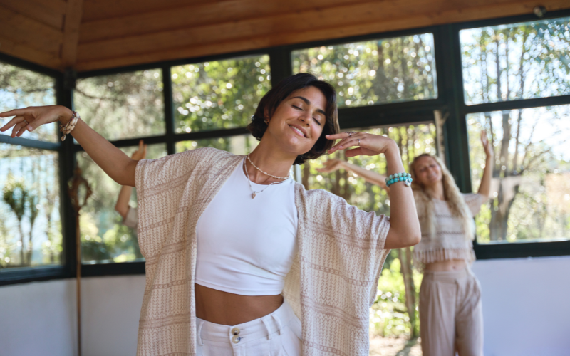 Smiling women practicing 5Rhythms dance in a sunlit room