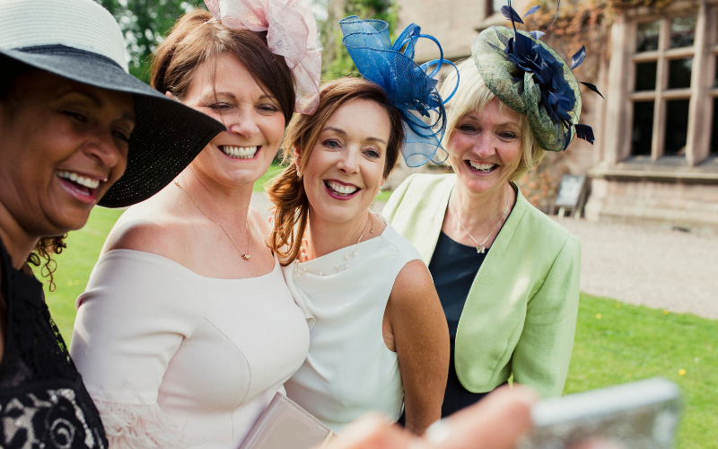 4 women posing together wearing fascinators