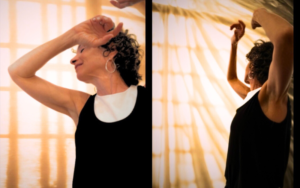 Julie Greenberg dancing against a cream silk background in a movement mediation workshop