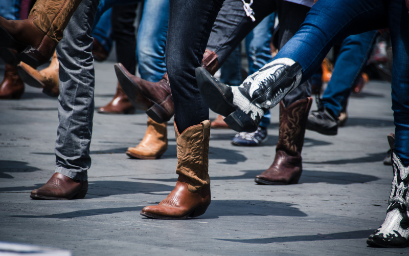 Group of people doing country line dancing while wearing cowboy boots