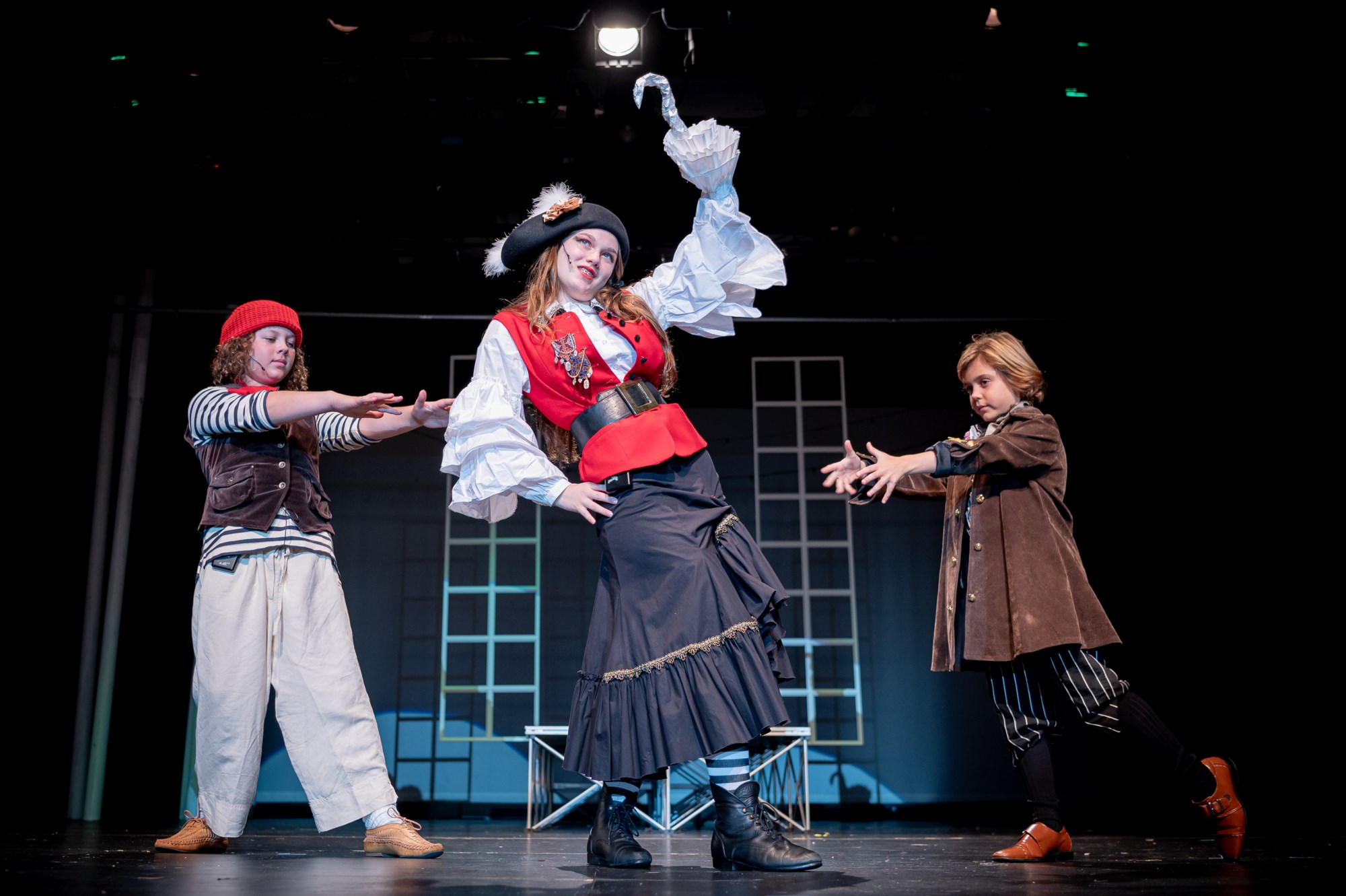 Girl in a pirate costume dancing with two other castmates dressed as pirates at a Peter Pan theatre performance