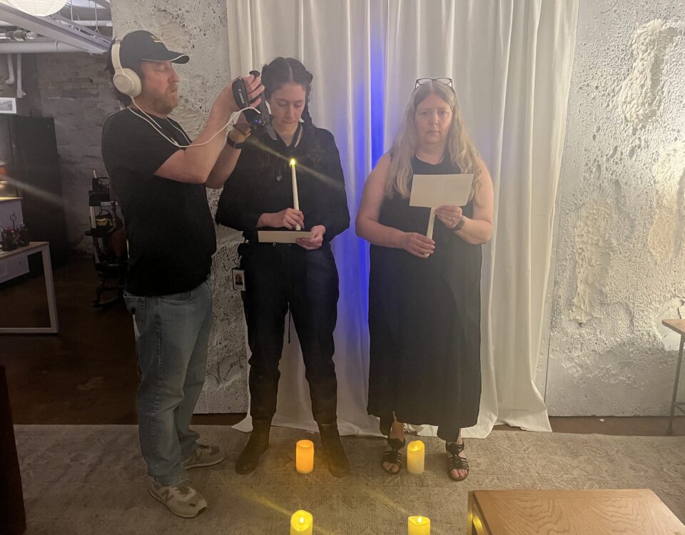 Jeremy Kruse holding a camera while two women use candles to act out a scene