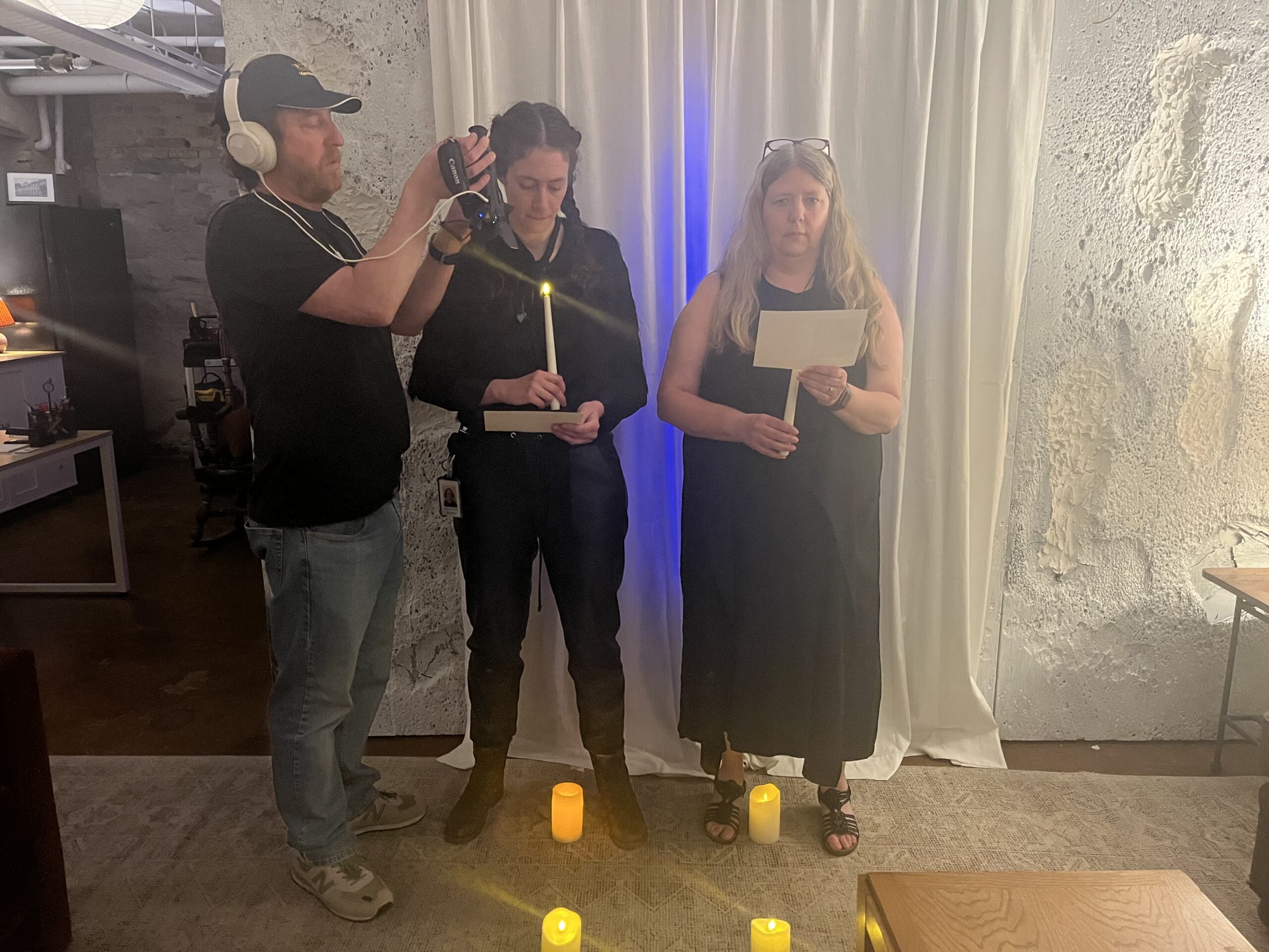Jeremy Kruse holding a camera while two women use candles to act out a scene