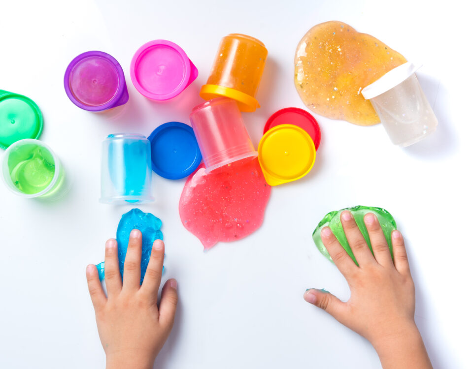 Child's hands playing with colorful slime on white background,top view.