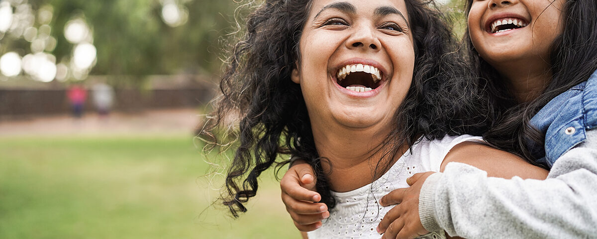 Happy mom and daughter outside laughing