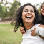 Happy mom and daughter outside laughing