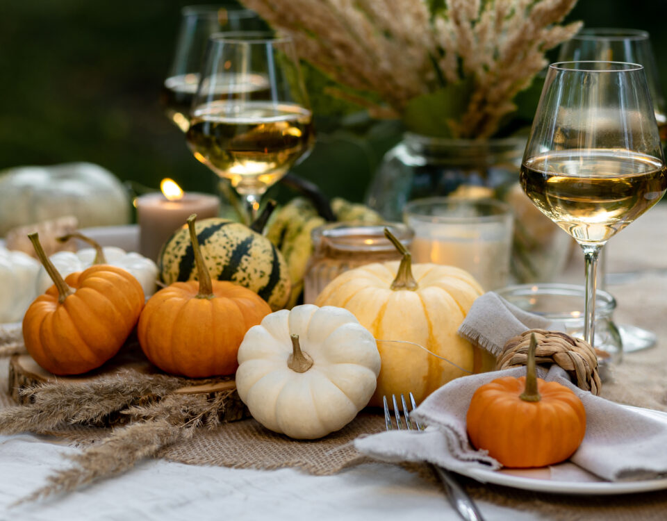 Fall table decoration with pumpkins, wine. Family thanksgiving dinner arrangement outdoors in the garden. Countryside style, simple handmade setting, autumn mood