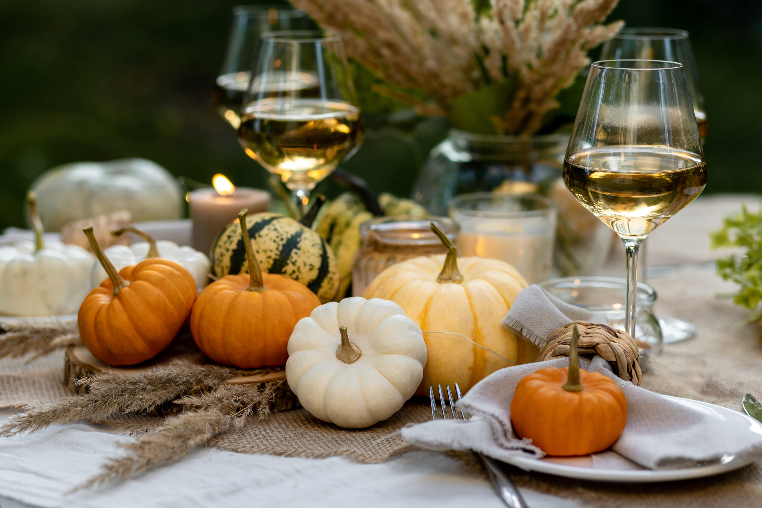 Fall table decoration with pumpkins, wine. Family thanksgiving dinner arrangement outdoors in the garden. Countryside style, simple handmade setting, autumn mood