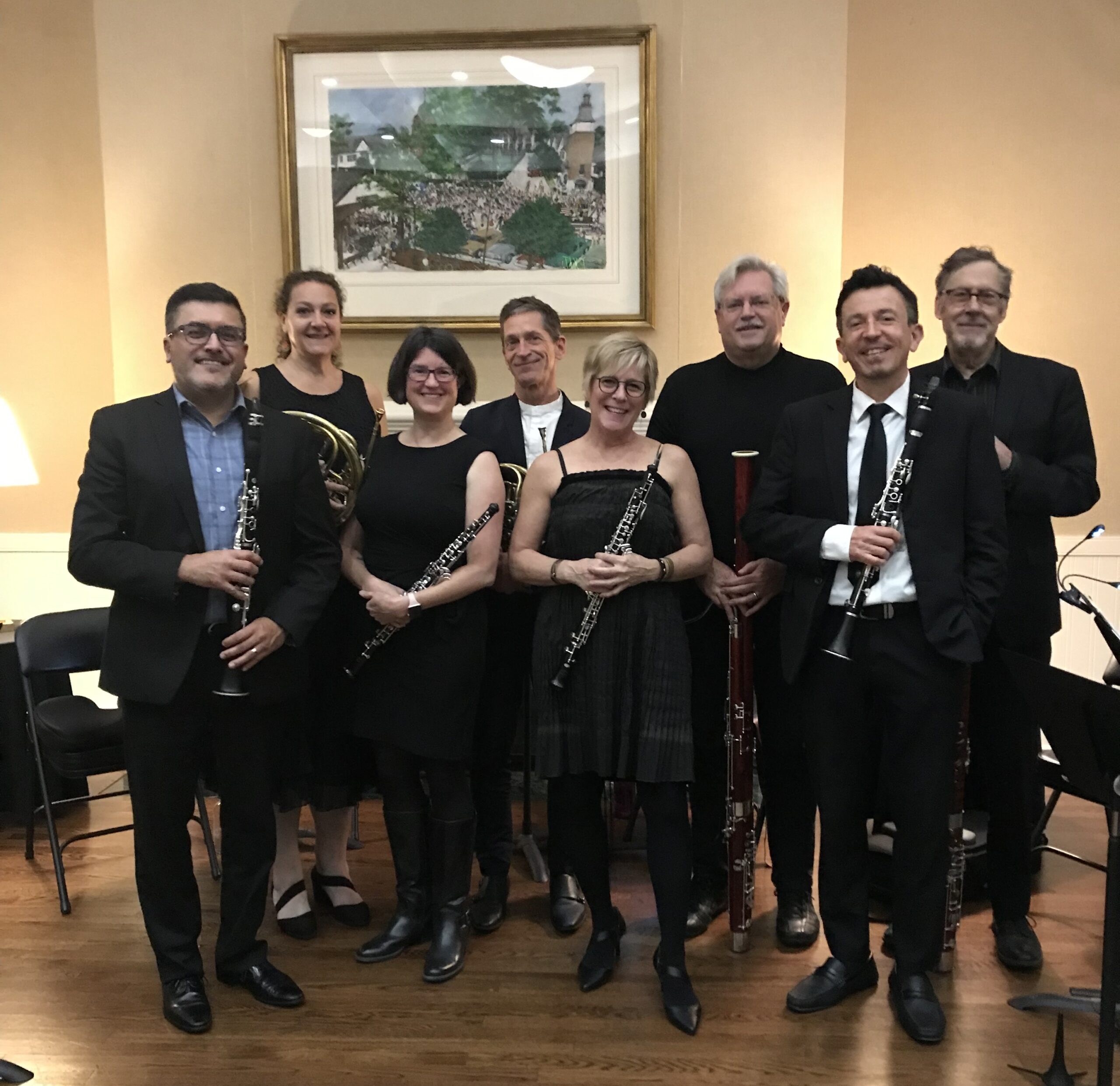 Members of the Woodwind celebration octet gathered in front of the mantel in the Stuart Community Room holding their instruments and looking at the camera