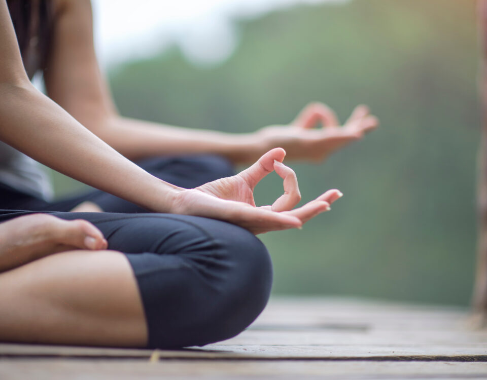 Woman yoga finger acting on hands in soft focus background with Nature surrounding