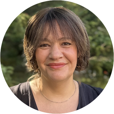 Portrait of Erica Maute, smiling, with green foliage in background