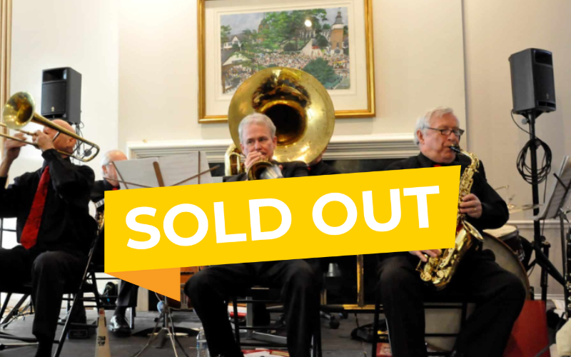 Members of Red Rose Jazz performing in the stuart room with a yellow 'sold out banner' over their picture