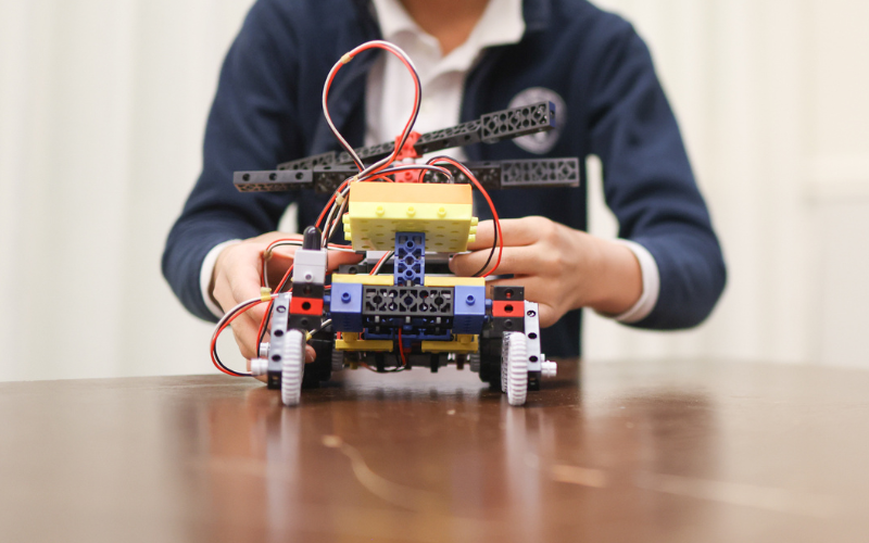 Closeup of a youth adjusting a RoboThink vehicle that sits on a table