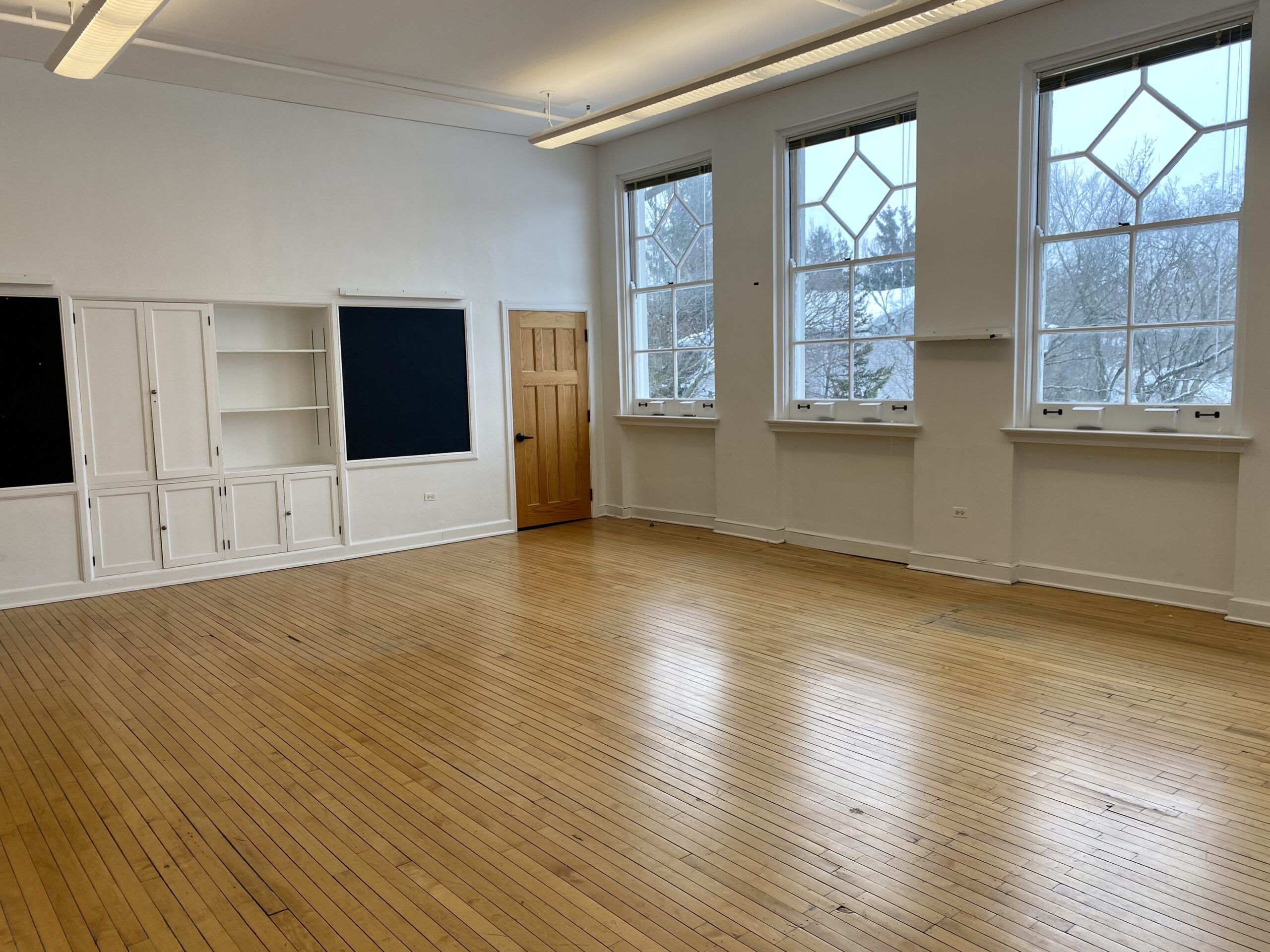 Room with large windows, hardwood floors and built in shelving, second floor rental room