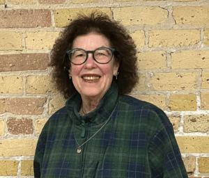 Do not submit host Lisa Parr is posing in front of the brick wall in the grotto and smiling directly at the camera