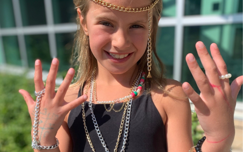 girl at jewelry camp with jewelry on her head, neck and fingers