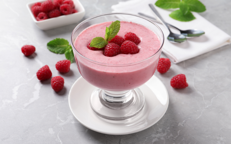 Raspberry mousse in a glass goblet topped with fresh raspberries