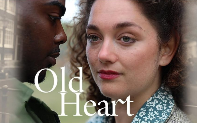 An image from the film "Old Heart"- A man and a woman are standing closely together- the man is looking at the woman while she stares off into the distance.
