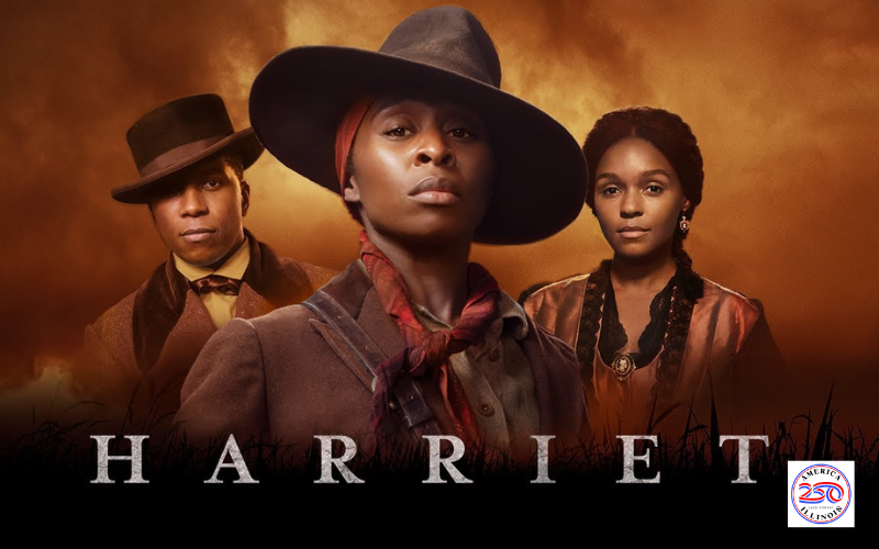 The official poster for the movie "Harriet". The poster features the 3 stars of the film; Cynthia Ervio as Harriet stands in the middle looking defiantly at the camera. Behind her and to her left is Leslie Odom Junior as William Still and behind and to her right is Janelle Monae as Marie Buchanon. They each have a small smile and are looking directly at the camera. In the lower right hand corner is the America 250 logo in red, white and blue.