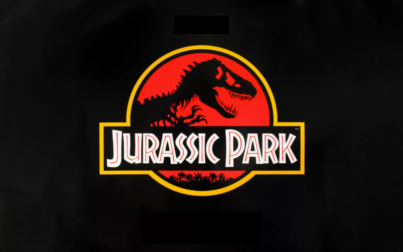 The skeleton of a t-rex in profile in the center of a red circle. Below that in white block letters with red line running through them it says "Jurassic Park"