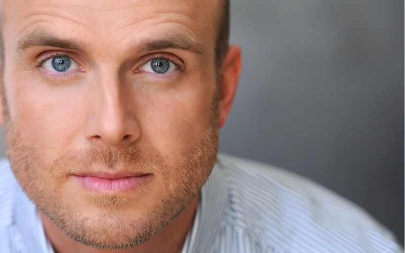Headshot of comedian Kellen Erskine. The camera is tight on his face- he has a serious expression and is looking directly into the camera.