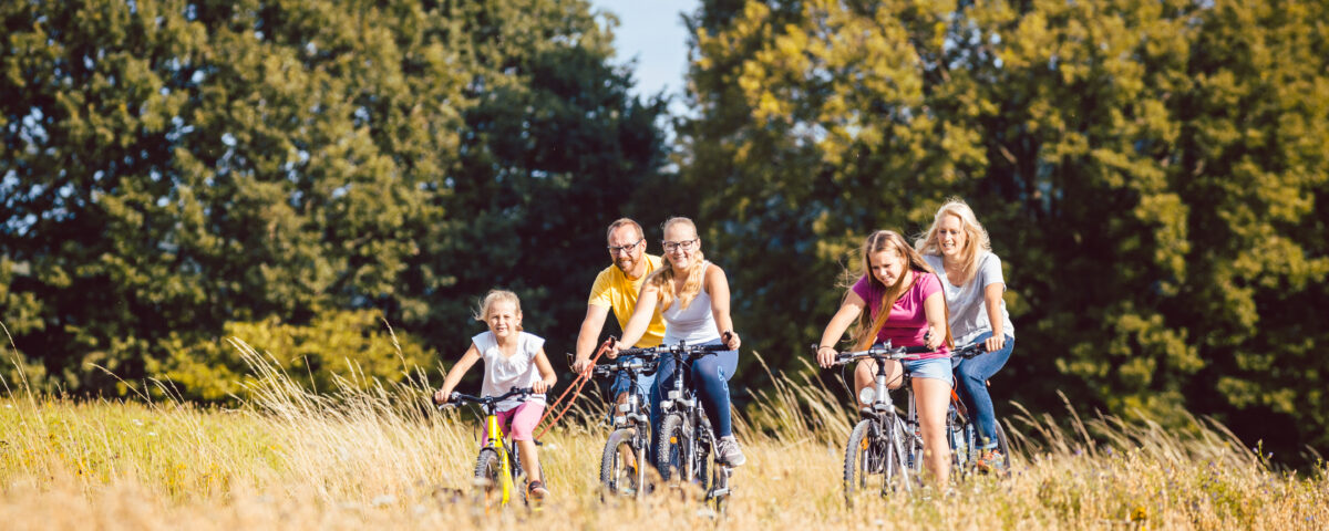 Adults and children riding bikes on path through nature area, family on bikes