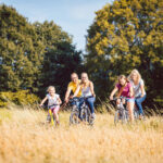 Adults and children riding bikes on path through nature area, family on bikes