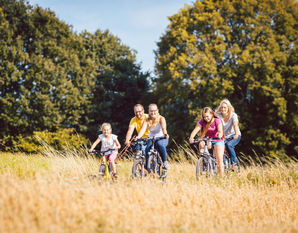 Adults and children riding bikes on path through nature area, family on bikes