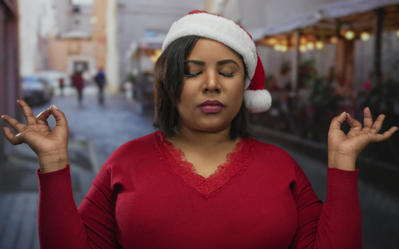 Festive Reset, woman in santa hat holding fingers in OM position