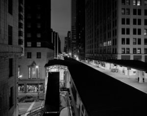 A black and white photo by Glenn Hanson of an 'EL' station in downtown Chicago at night. 